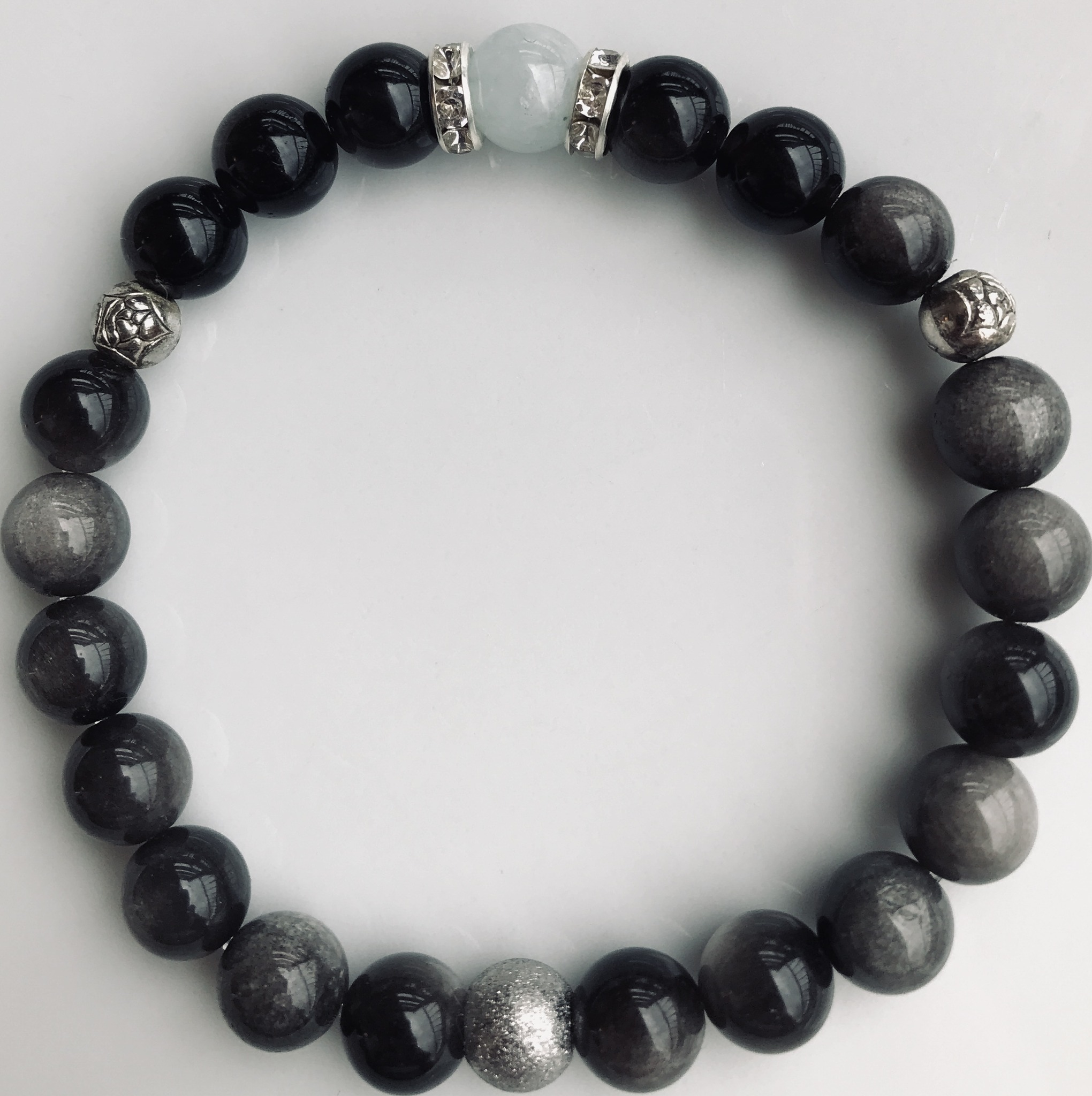 Bracelet composé d’Obsidienne argentée et d’une perle centrale d’Aigue Marine (pierres de 8mm).